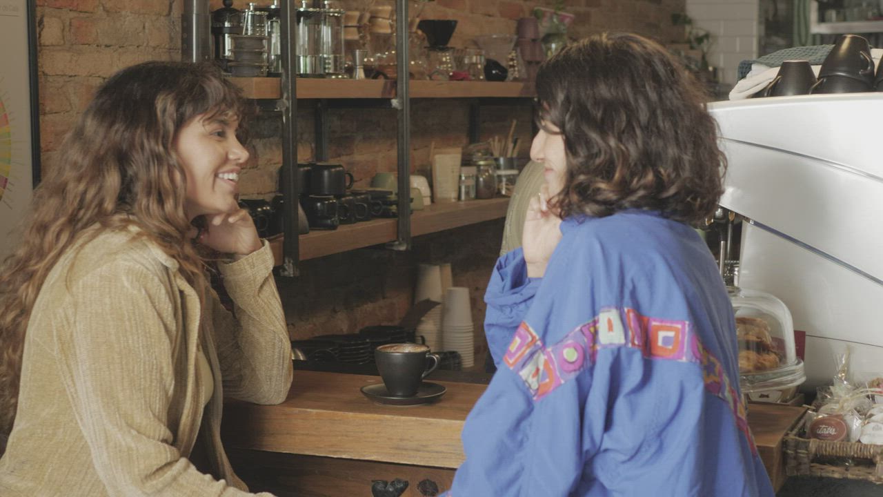 Two friends talking over coffee at a café counter