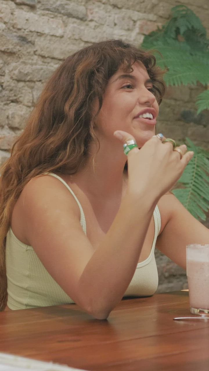 A woman laughing mid-conversation at a wooden table