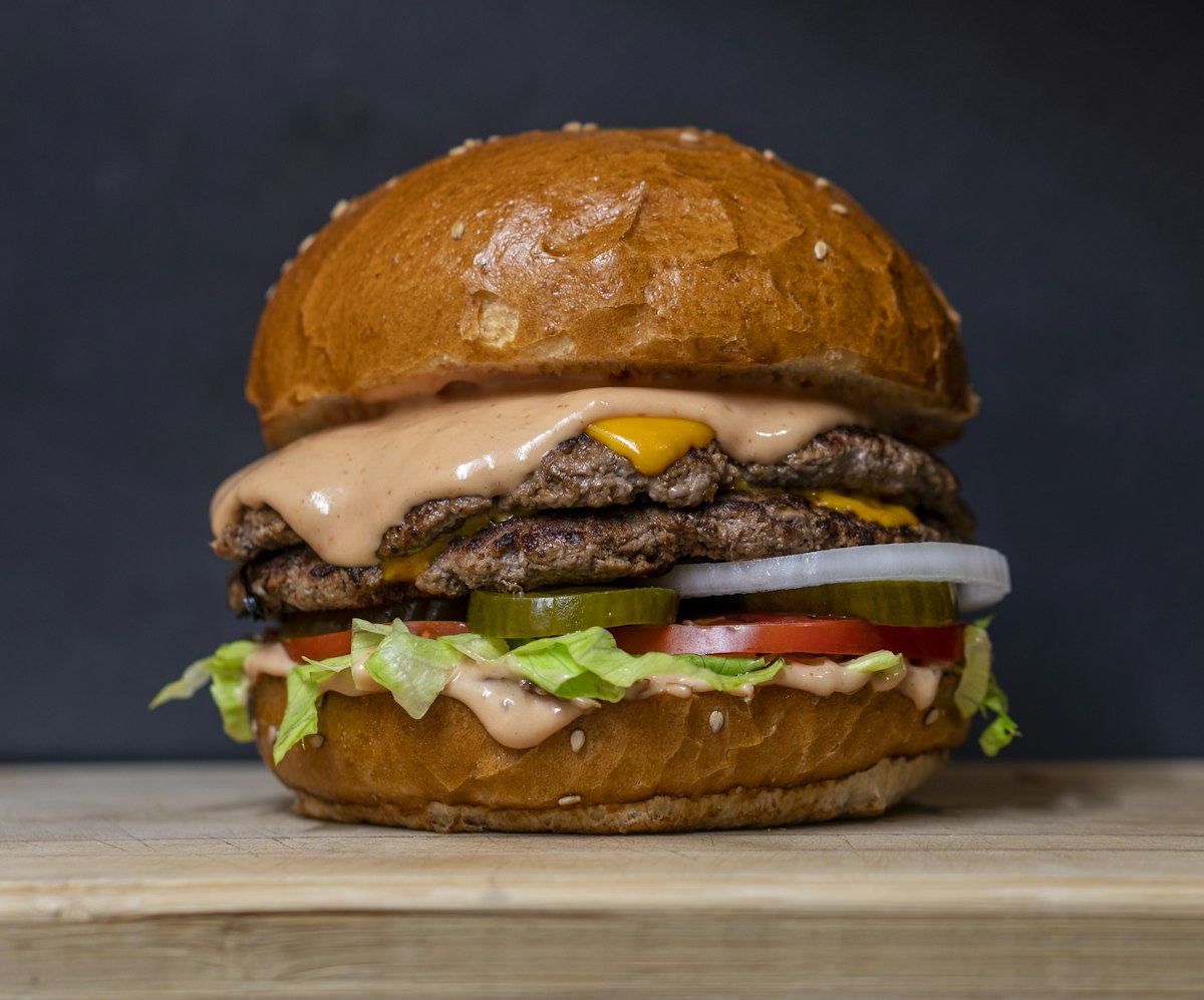 A double cheeseburger against a dark background